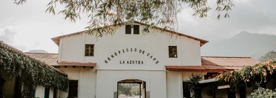 Charming historic building of Beneficio de Cafe La Azotea surrounded by lush greenery and cobblestones.