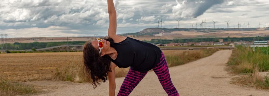 Outdoor fitness scene of a woman stretching on a dirt path in Soto de Cerrato amidst scenic landscapes.